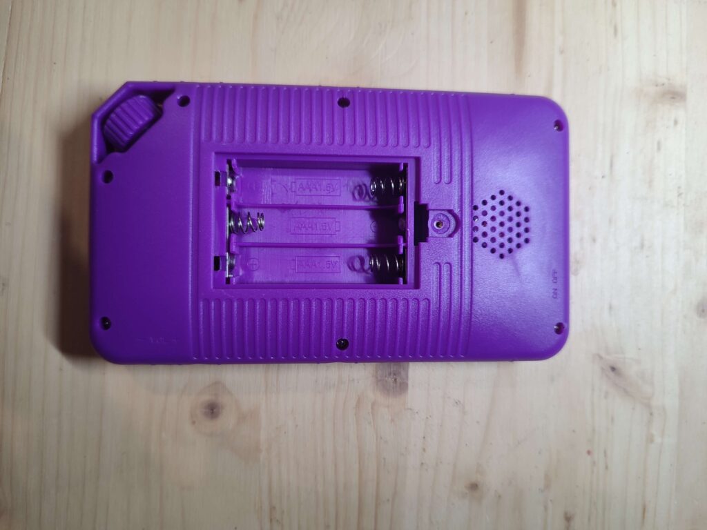 Dos de la console rétro : compartiment ouvert accueillant les 3 piles AAA de 1,5 V